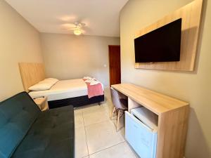 a small room with a bed and a flat screen tv at Summer Suítes - Passagem in Cabo Frio