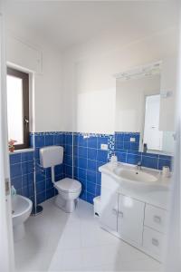 La salle de bains est pourvue de carrelage bleu, de toilettes et d'un lavabo. dans l'établissement Le Terrazze in Villa, à Reitano