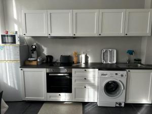 a kitchen with white cabinets and a washing machine at Appartement diamant in Brussels