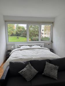 Un dormitorio con una cama grande y dos ventanas. en Chambre calme et confortable, accès aux pièces de vie, avec vue sur Parc, en Ginebra