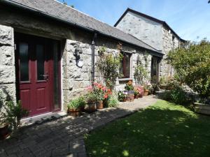 a stone house with a red door and some plants at Brunnion Cottage in Hayle
