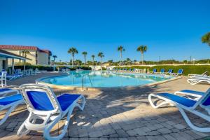 a pool with blue and white chairs and palm trees at St. Augustine Condo Near Flagler College & Beach! in Coquina Gables