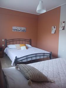 twee bedden in een slaapkamer met oranje muren bij Village perfume in Kalavrita