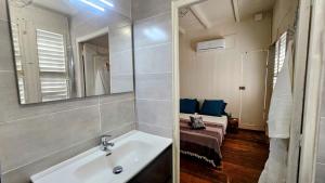 a bathroom with a sink and a mirror and a bed at Katarina in Sainte-Thérèse