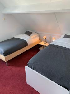 a bedroom with two beds and two tables with lamps at Wellness huis voor 6 personen aan het strand 'Zeeuwse Rust' in Wemeldinge