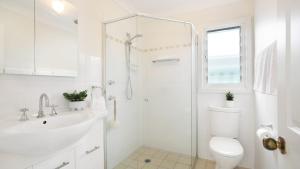 a white bathroom with a toilet and a sink at Rockpool Retreat in Currarong +18 photos