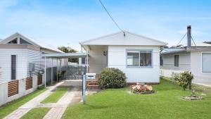 a white house with a lawn in front of it at Rockpool Retreat in Currarong