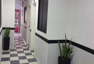 a hallway with potted plants on a checkered floor at Hotel Playa Itagui in Itagüí