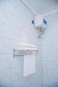 a white tiled bathroom with white towels on a rack at The House in Kampala