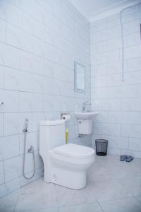 a white bathroom with a toilet and a sink at The House in Kampala +7 photos