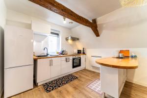 a kitchen with white cabinets and a wooden counter top at Le Nid - Hypercentre - 3 beds - Wifi - Netflix in Cambrai