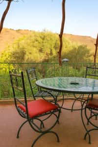 a glass table and chairs on a balcony with a table and chairs at DAR Moha dades in Aït Ougliff