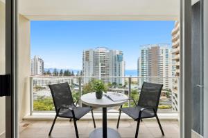 Un balcón con mesa y sillas y una gran ventana. en Coastal 1-Bed Escape Located in Twin Towns, en Tweed Heads