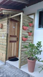 a wooden dog house with potted plants next to a door at Suite 66 privativa, 11km da vila Germânica in Blumenau