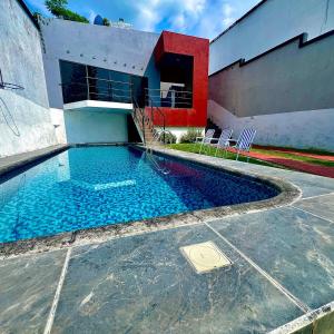 a swimming pool with chairs next to a building at Casa con alberca en Morelos in Barranca Honda