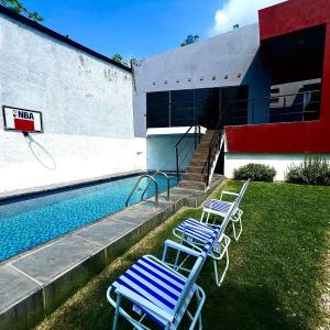 two blue chairs sitting next to a swimming pool at Casa con alberca en Morelos in Barranca Honda