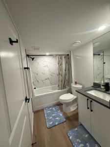 a bathroom with a tub and a toilet and a sink at Cozy 2 Bedroom Suite Close to Amenities in Edmonton