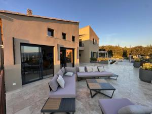 eine Terrasse mit Sofas und Tischen vor einem Gebäude in der Unterkunft Sunny Year-Round Provençal Luxury Retreat in Saint-Saturnin-dʼApt