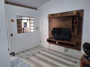 a living room with a flat screen tv on a wall at Casa entre a praia do Curral e cachoeira in Ilhabela