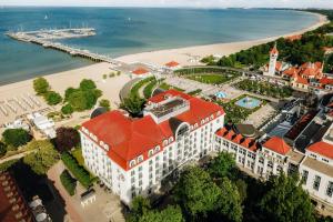 a building with a red roof next to a beach at Sheraton Sopot Hotel in Sopot