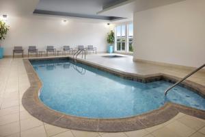 a pool in a hotel room with chairs and tables at SpringHill Suites by Marriott Wichita Airport in Wichita