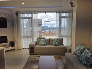 uma sala de estar com um sofá e uma janela grande em Horizonte Mágico full suite em Cuenca