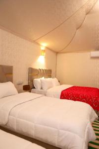 a hotel room with two beds and a red blanket at Desert Agafay Luxury Camp in El Karia