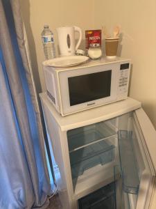een magnetron bovenop een plank bij Quarto privativo em uma casa com outros quartos e banheiro compartilhado in Peterborough