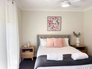 a bedroom with a bed with pink and white pillows at Glen's Gibson St Getaway in North Wagga