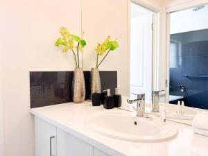 a bathroom with a sink and two vases with flowers at Glen's Gibson St Getaway in North Wagga +35 photos