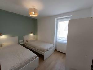 Un dormitorio con dos camas y una ventana. en Le Lila, en Cholet