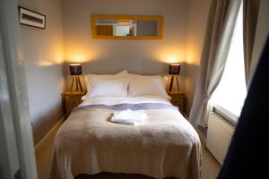 a bed in a bedroom with two lamps and a mirror at Wynstone Cottage, Speyside in Fochabers