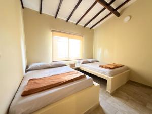 two beds in a room with a window at La Palma family cabin in San Antero