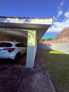 a white car is parked under a garage at Casa Aconchegante in Foz do Iguaçu
