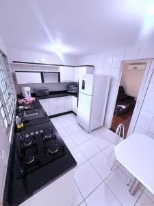 a white kitchen with a stove and a refrigerator at Casa Aconchegante in Foz do Iguaçu