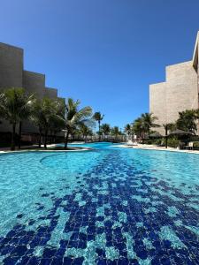 una grande piscina di acqua blu con palme e edifici di Apto no Porto das Dunas - Scopa Beach ad Aquiraz