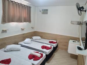 a room with two beds with red towels on them at Pousada Quarto tv Smart ar Garagem Gratuita in Aparecida