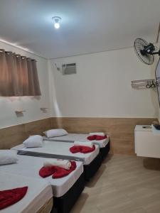 a room with three beds with red towels on them at Pousada Quarto tv Smart ar Garagem Gratuita in Aparecida