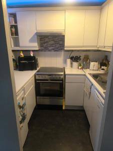 a small kitchen with white cabinets and a stove at Angelo's home in London +6 photos