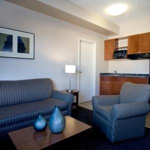 ein Wohnzimmer mit einer Couch, einem Sessel und einem Tisch in der Unterkunft Heritage Inn & Suites - Brooks in Brooks