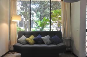 a couch with pillows on it in front of a window at Laureles, casa completa y amplia para grupos grandes in Medellín