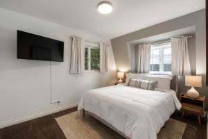 a bedroom with a white bed and a flat screen tv at Hood Canal Escape- upscale meets the rocky shores! in Belfair