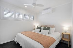 a white bedroom with a large bed with pillows at Alba on Ocean in Casuarina