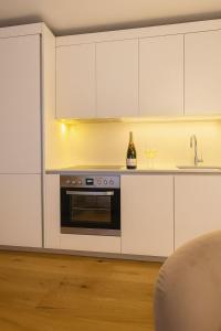 a kitchen with white cabinets and a sink and a oven at Lux Line Apartment in Zürich
