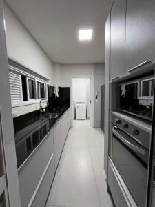 a kitchen with black and white counters and appliances at Apto a 200mts do mar Meia Praia - Itapema in Itapema