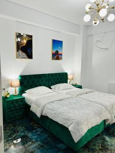 a bedroom with a large bed with a green headboard at Pensiunea Gloria in Afumaţi