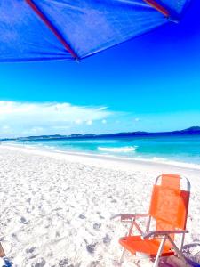 a beach chair and an umbrella on a beach at Suíte 21 com tv, frigobar, mesa de trabalho, decorada e banheiro privativo in Cabo Frio