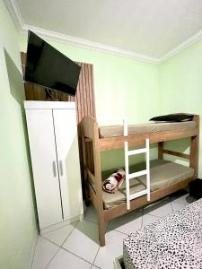 a small room with a bunk bed and a chair at Suíte 21 com tv, frigobar, mesa de trabalho, decorada e banheiro privativo in Cabo Frio