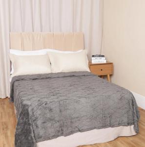 a bed with a gray blanket and a night stand at Flat para até 6 pessoas em Nossa Sra do Ó in Ipojuca