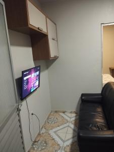 Una sala de estar con un sofá y un televisor en una pared. en Residencial Humberto Mendes, en Belém